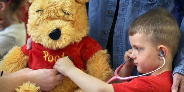 Ein kleiner Junge hört mit einem Stethoskop einen Teddybär ab. Ein kleiner Junge hört mit einem Stethoskop einen Teddybär ab.