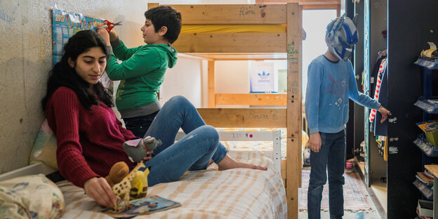 Drei Kinder sitzen bzw. stehen in einem engen Kinderzimmer Drei Kinder sitzen bzw. stehen in einem engen Kinderzimmer