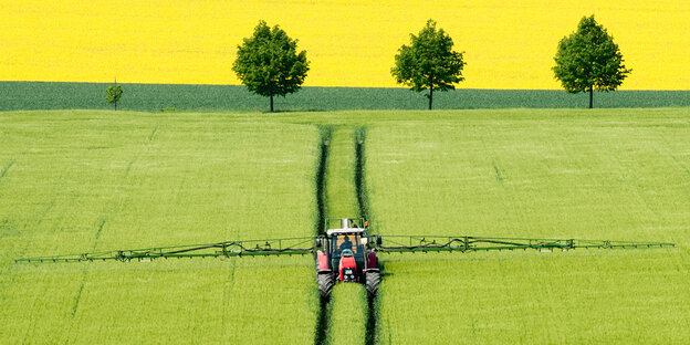 Ein Tracktor verteilt Pestizid auf einem Feld Ein Tracktor verteilt Pestizid auf einem Feld