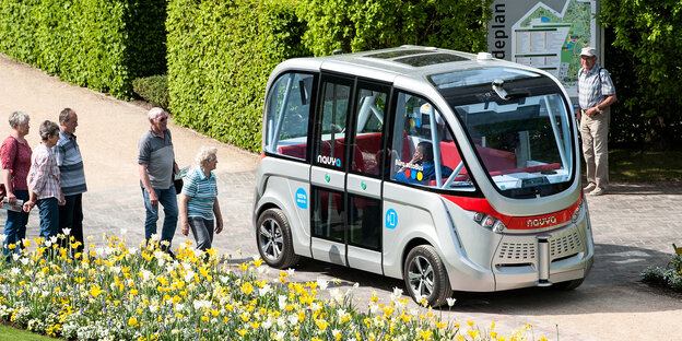 Fünf Menschen bewegen sich auf einen selbstfahrenden Bus zu