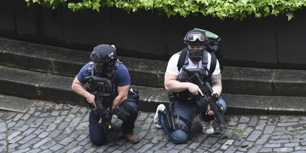 Zwei bewaffnete Polizisten knien in Deckung Zwei bewaffnete Polizisten knien in Deckung