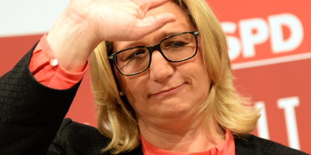 Eine Frau winkt, ihr Gesicht sieht enttäuscht aus Eine Frau winkt, ihr Gesicht sieht enttäuscht aus