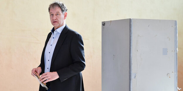 Ein Mann neben einer Wahlkabine Ein Mann neben einer Wahlkabine