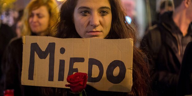 Eine Frau hält ein Schild und eine Rose in ihren Händen. Ihre Wimperntusche ist verschmiert Eine Frau hält ein Schild und eine Rose in ihren Händen. Ihre Wimperntusche ist verschmiert