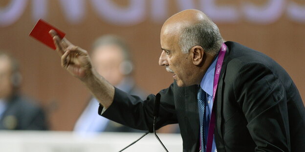 Jibril Rajoub steht an einem Rednerpult und hält eine rote Papierkarte in der Hand Jibril Rajoub steht an einem Rednerpult und hält eine rote Papierkarte in der Hand