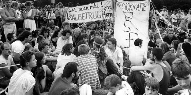 Eine Gruppe junger Leute sitz mit Spruchbändern auf dem Boden Eine Gruppe junger Leute sitz mit Spruchbändern auf dem Boden