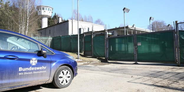 Ein blaues Auto vor einem grünen Kasernentor Ein blaues Auto vor einem grünen Kasernentor