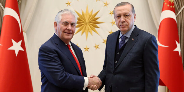 Rex Tillerson und Erdogan halten jeweils die Hand des anderen und starren in die Kamera Rex Tillerson und Erdogan halten jeweils die Hand des anderen und starren in die Kamera