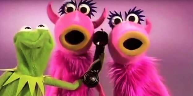 Ein Screenshot aus dem Youtube-Video der Muppetshow: zwei pinke Zottelmonster, die singen und Kermit, der ihnen einen Telefonhörer hinhält Ein Screenshot aus dem Youtube-Video der Muppetshow: zwei pinke Zottelmonster, die singen und Kermit, der ihnen einen Telefonhörer hinhält