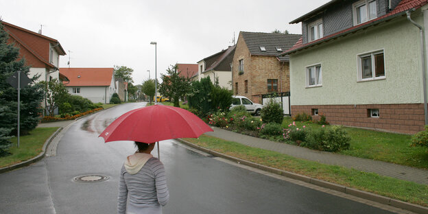 Eine Frau mit Schirm in einem Dorf Eine Frau mit Schirm in einem Dorf