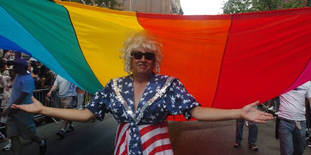 Eine Person in US-Farben gekleidet unter einer Regenbogenflagge Eine Person in US-Farben gekleidet unter einer Regenbogenflagge
