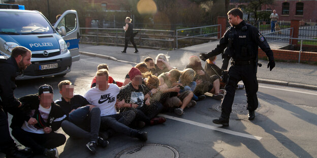 Ein Polizist sprüht Demonstranten einer Sitzblockade Pfefferspray ins Gesicht Ein Polizist sprüht Demonstranten einer Sitzblockade Pfefferspray ins Gesicht