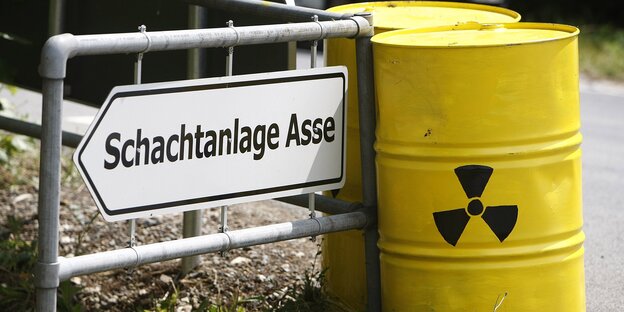 Zwei gelbe Atommüll-Fässer neben einem Asse-Schild. Zwei gelbe Atommüll-Fässer neben einem Asse-Schild.