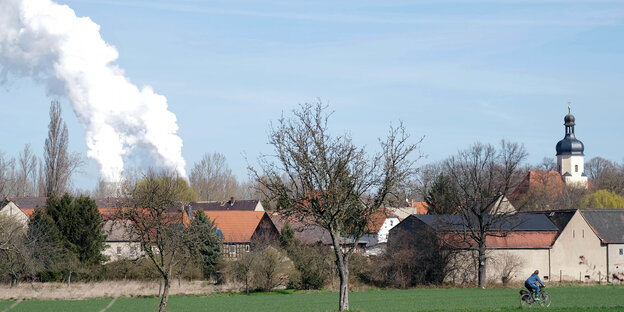 Ein kleiner Ort aus der Ferne fotografiert, hinter dem ein großer Rauchschwaden empor steigt Ein kleiner Ort aus der Ferne fotografiert, hinter dem ein großer Rauchschwaden empor steigt