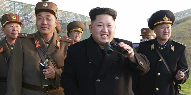 Kim Jong Un hat ein Fernglas in der Hand und blickt in die gleiche Richtung, wie die vier Uniform tragenden Männer hinter ihm Kim Jong Un hat ein Fernglas in der Hand und blickt in die gleiche Richtung, wie die vier Uniform tragenden Männer hinter ihm