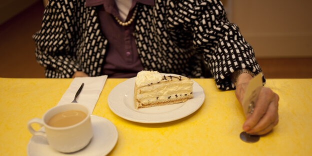 Demenzkranke Frau im Pflegeheim vor ihr steht ein Stück Kuchen und eine Tasse Kaffee Demenzkranke Frau im Pflegeheim vor ihr steht ein Stück Kuchen und eine Tasse Kaffee