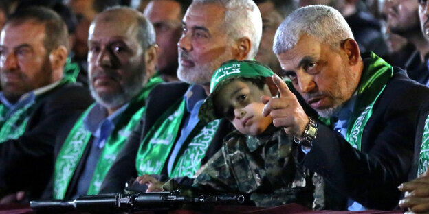 Der neue Chef der Hamas, Jihia al-Sinwar, neben einem kleinen Jungen, vor dem ein Gewehr liegt Der neue Chef der Hamas, Jihia al-Sinwar, neben einem kleinen Jungen, vor dem ein Gewehr liegt