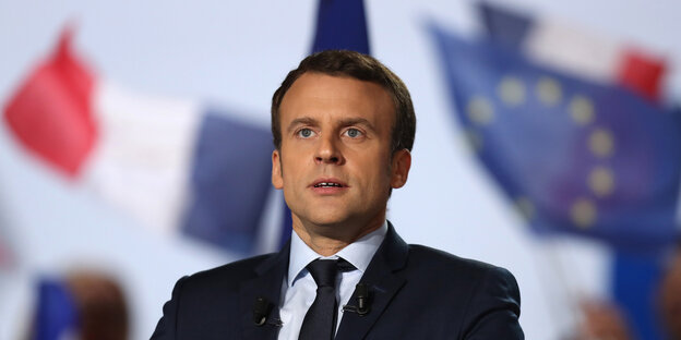 Emmanuel Macron steht vor der französischen und der europäischen Flagge Emmanuel Macron steht vor der französischen und der europäischen Flagge