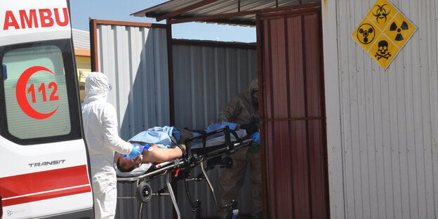 Sanitäter bringen einen Verletzten in einen Container Sanitäter bringen einen Verletzten in einen Container