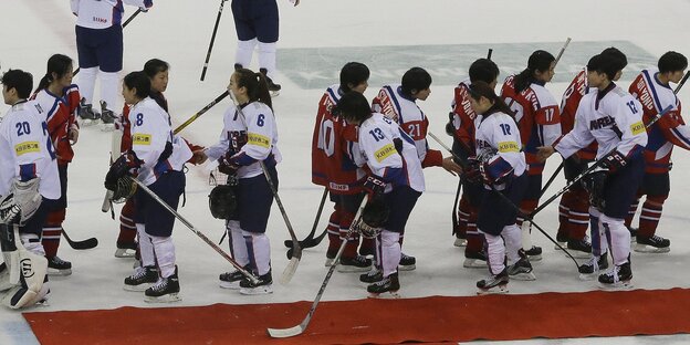Nord- und südkoreanische Eishockeyspielerinnen schütteln sich nach dem Spiel die Hände Nord- und südkoreanische Eishockeyspielerinnen schütteln sich nach dem Spiel die Hände