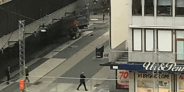 Die Rückseite eines Lastwagens ragt aus einer Kaufhausfassade, Rauch steigt auf Die Rückseite eines Lastwagens ragt aus einer Kaufhausfassade, Rauch steigt auf