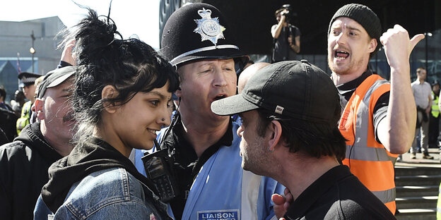 Eine Frau stellt sich einem rechten Demonstranten entgegen, umringt von Polizisten Eine Frau stellt sich einem rechten Demonstranten entgegen, umringt von Polizisten