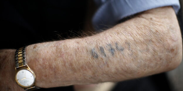 Ein Holocaust-Überlebender zeigt seinen Arm mit der tätowierten Nummer Ein Holocaust-Überlebender zeigt seinen Arm mit der tätowierten Nummer