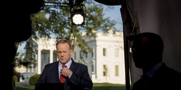 Sean Spicer steht im Schatten vor dem in der Sonne stahlenden weißen Haus Sean Spicer steht im Schatten vor dem in der Sonne stahlenden weißen Haus