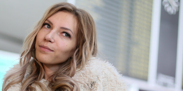 Eine blonde Frau mit gelocktem Haar, die nach rechts blickt