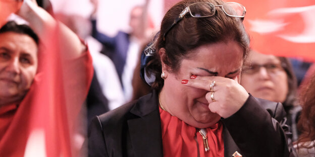 Eine Frau hält sich weinend eine Hand vor die Augen Eine Frau hält sich weinend eine Hand vor die Augen