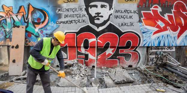 Ein Mann fegt vor einem Grafitti, das Atatürks Porträt zeigt, darunter der Schriftzug „1923“ Ein Mann fegt vor einem Grafitti, das Atatürks Porträt zeigt, darunter der Schriftzug „1923“