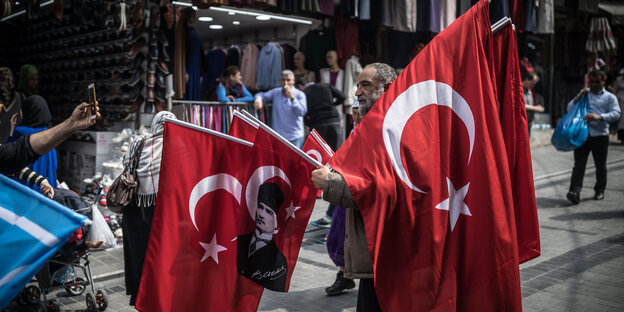 Ein Händler trägt türkische Fahnen, die über seinen Körper hängen Ein Händler trägt türkische Fahnen, die über seinen Körper hängen