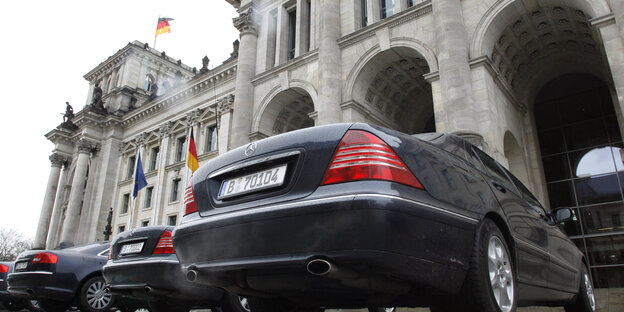 Mehrere schwarze Autos nebeneinander von unten fotografiert, im Hintergrund ein Bundestagsgebäude Mehrere schwarze Autos nebeneinander von unten fotografiert, im Hintergrund ein Bundestagsgebäude