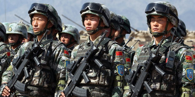 Drei Soldaten stehen in Reih und Glied einer größeren Gruppe von Soldaten Drei Soldaten stehen in Reih und Glied einer größeren Gruppe von Soldaten