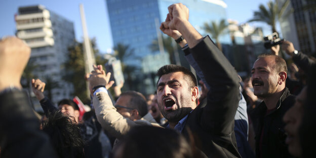 Ein wütender türkischer Demonstrant hat kämpferisch die linke Faust geballt, hinter ihm weitere Demonstranten Ein wütender türkischer Demonstrant hat kämpferisch die linke Faust geballt, hinter ihm weitere Demonstranten