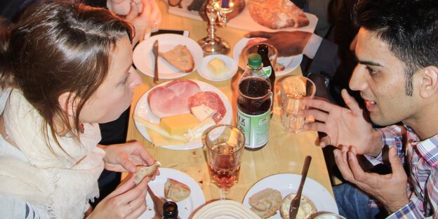 Menschen unterhalten sich an gedecktem Tisch Menschen unterhalten sich an gedecktem Tisch