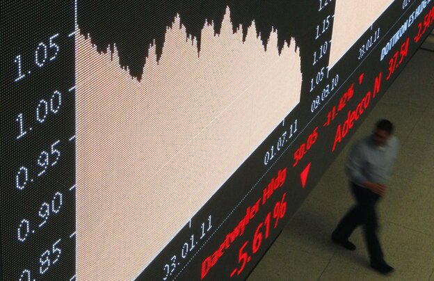 Eine Anzeigentafel in der Börse zeigt fallende Kurse, im Hintergrund läuft ein Mann vorbei Eine Anzeigentafel in der Börse zeigt fallende Kurse, im Hintergrund läuft ein Mann vorbei