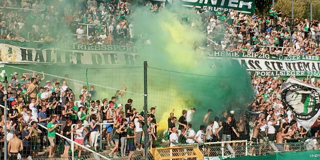 eine volle Fankurve hinter grünem Rauch eine volle Fankurve hinter grünem Rauch