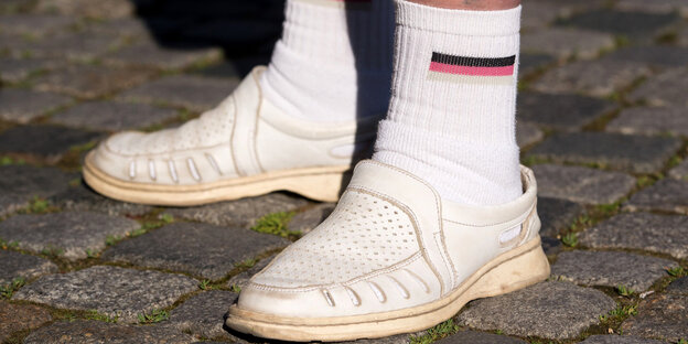Füße eines Pegida-Teilnehmers in weißen Schuhen und Socken mit der Deutschland-Fahne Füße eines Pegida-Teilnehmers in weißen Schuhen und Socken mit der Deutschland-Fahne