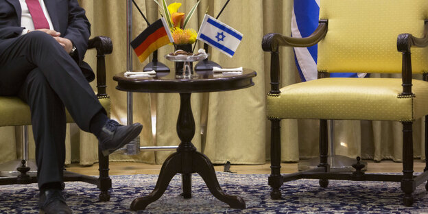 Sigmar Gabriel sitzt auf einem Stuhl, der Stuhl neben ihm ist leer. Im Hintergrund deutsche und israelische Fahnen Sigmar Gabriel sitzt auf einem Stuhl, der Stuhl neben ihm ist leer. Im Hintergrund deutsche und israelische Fahnen