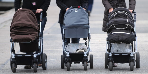 Drei Menschen schieben Kinderwagen Drei Menschen schieben Kinderwagen