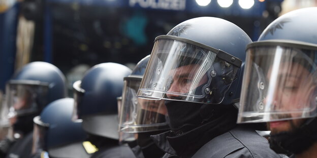 Behelmte Polizisten vor einem Wasserwerfer Behelmte Polizisten vor einem Wasserwerfer