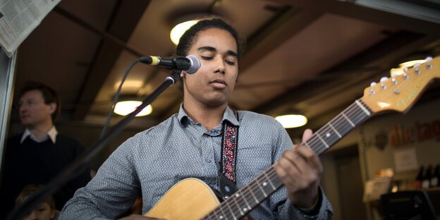 taz.meinland Mitarbeiter Samba Gueye spielt Gitarre taz.meinland Mitarbeiter Samba Gueye spielt Gitarre