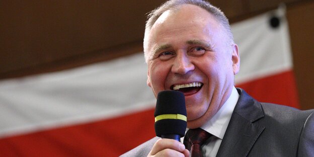 Nikolai Statkewitsch spricht in ein Mikrofon und lacht Nikolai Statkewitsch spricht in ein Mikrofon und lacht