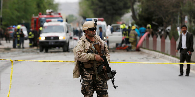 Ein afghanischer Sicherheitsmann steht mit Waffe im Arm hinter einem gelben Absperrband Ein afghanischer Sicherheitsmann steht mit Waffe im Arm hinter einem gelben Absperrband