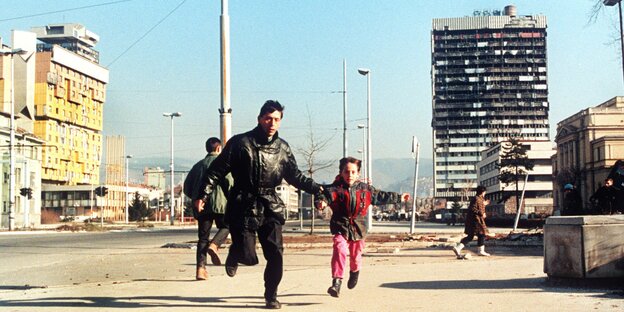 Ein Mann mit einem kleinen Mädchen an der Hand rennt auf der Flucht vor Heckenschützen durch Sarajevo Ein Mann mit einem kleinen Mädchen an der Hand rennt auf der Flucht vor Heckenschützen durch Sarajevo