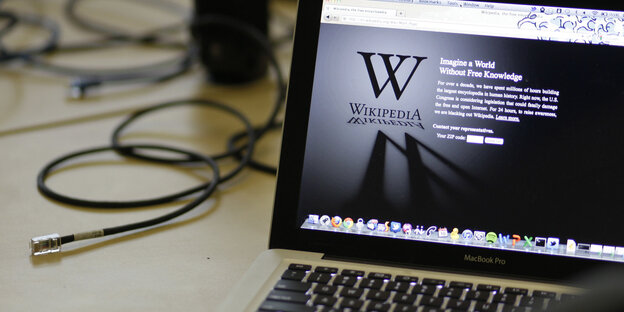 Ein Laptop mit einem Wikipedia-Logo und dem Text "Imagine a world without free knowledge" auf dem Bildschirm Ein Laptop mit einem Wikipedia-Logo und dem Text "Imagine a world without free knowledge" auf dem Bildschirm