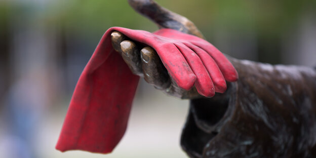 Die Hand einer Statue hält einen roten Handschuh Die Hand einer Statue hält einen roten Handschuh