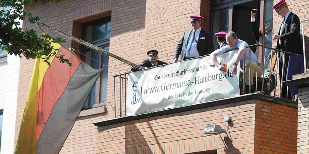 Alberne Männer sitzen mit albernen Mützen und Deutschlandfahne auf einem Balkon Alberne Männer sitzen mit albernen Mützen und Deutschlandfahne auf einem Balkon