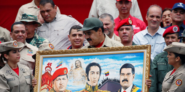 Nicolas Maduro hält ein Ölgemälde in der Hand. Er ist von Menschen in Uniform umringt Nicolas Maduro hält ein Ölgemälde in der Hand. Er ist von Menschen in Uniform umringt